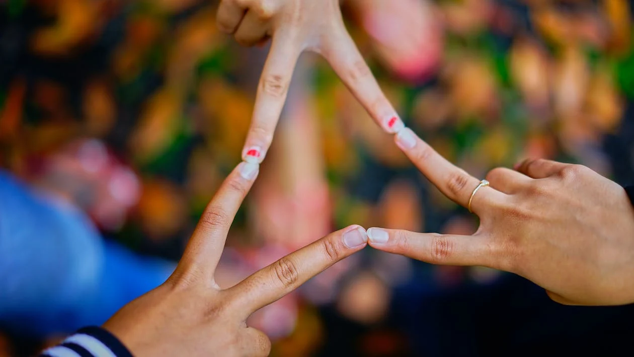 Photography of People Connecting Their Fingers in the Shape of a Triangle.

