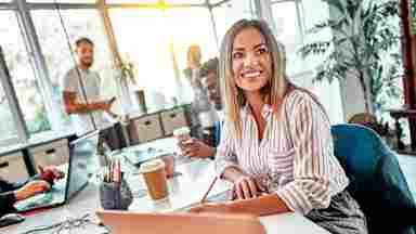 A happy businesswoman in an office meeting with her male co-workers. Woman. 