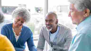 Diverse group of senior adults coming together at a support group and listening attentively to one another.