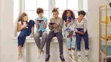 Diverse group of children playing on smartphones, reading, on social networks