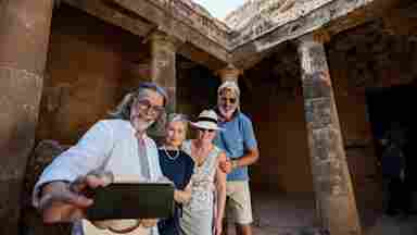 Mature tourist friends visiting tombs of the kings necropolis on Paphos, Cyprus.
