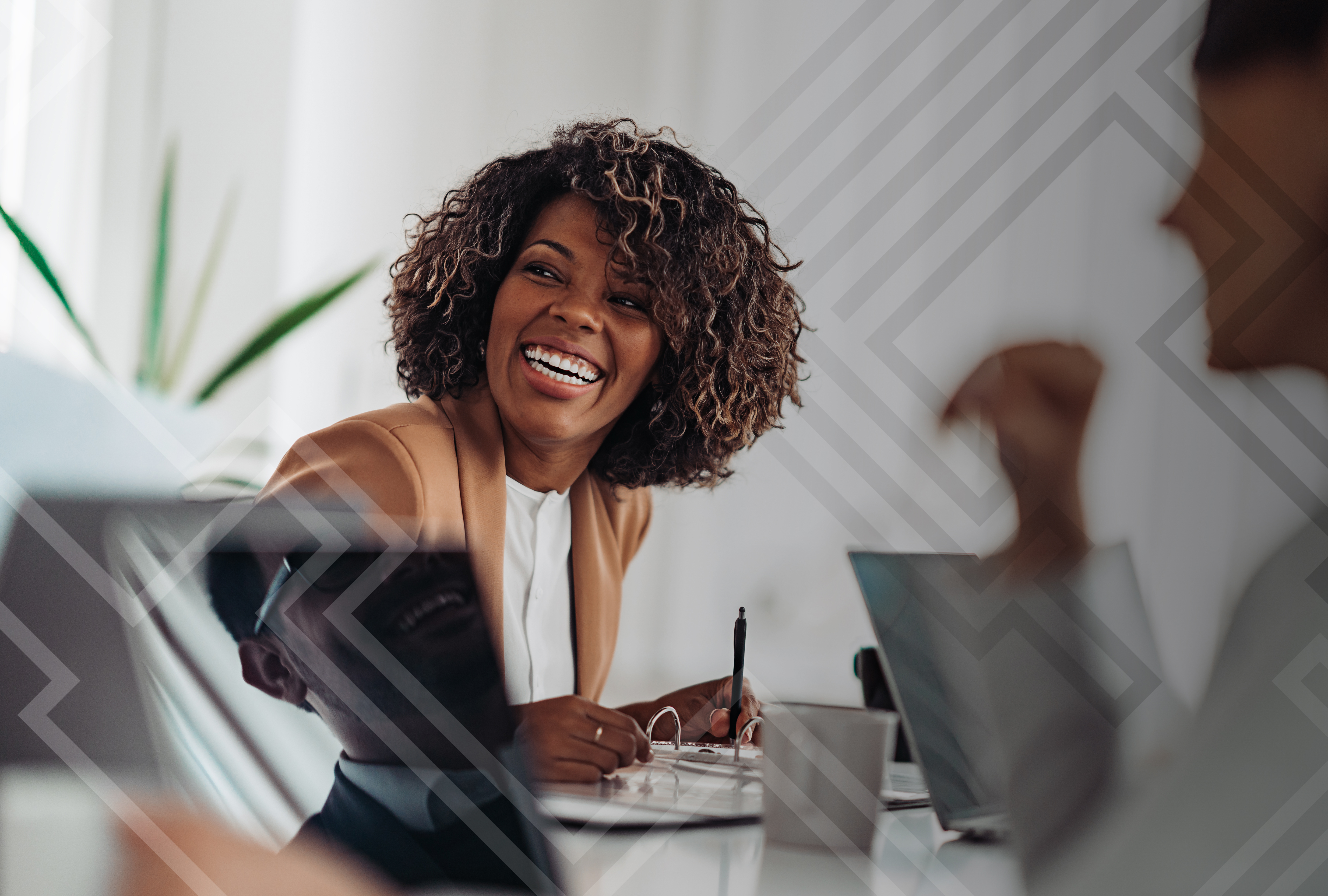 A smiling black woman sitting in a meeting.