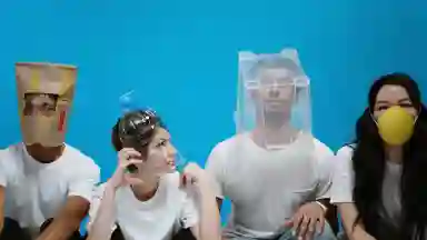 People sitting next to each other in a line wearing objects over their heads as diy masks