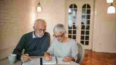 Senior couple seated together while working on their expenses. 