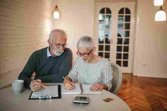 A senior couple seated together while working on their expenses at home.