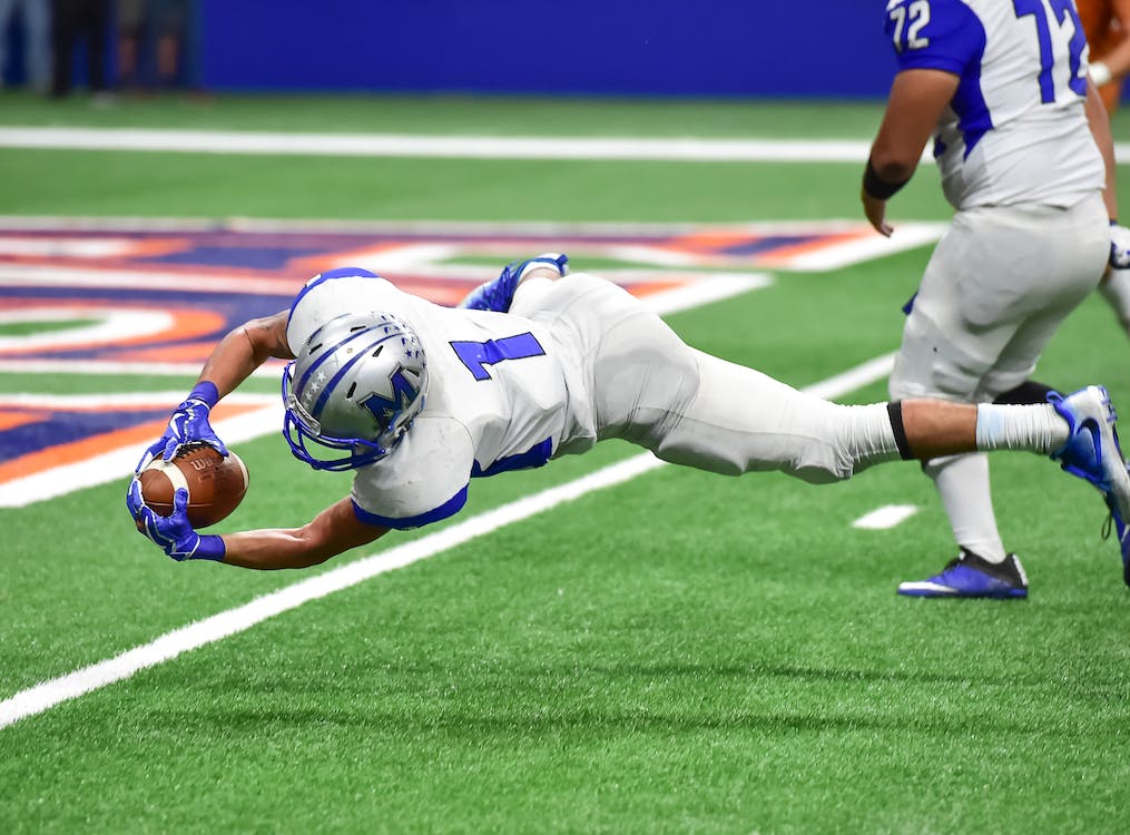 A football player dives for the ball