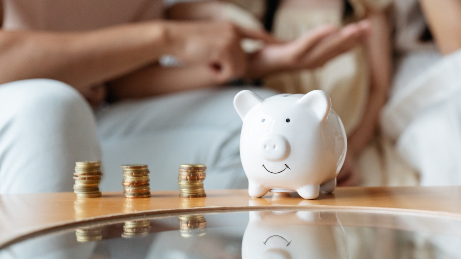 Close-up of an Asian family with child, counting coins to save in a cheerful ceramic piggybank.