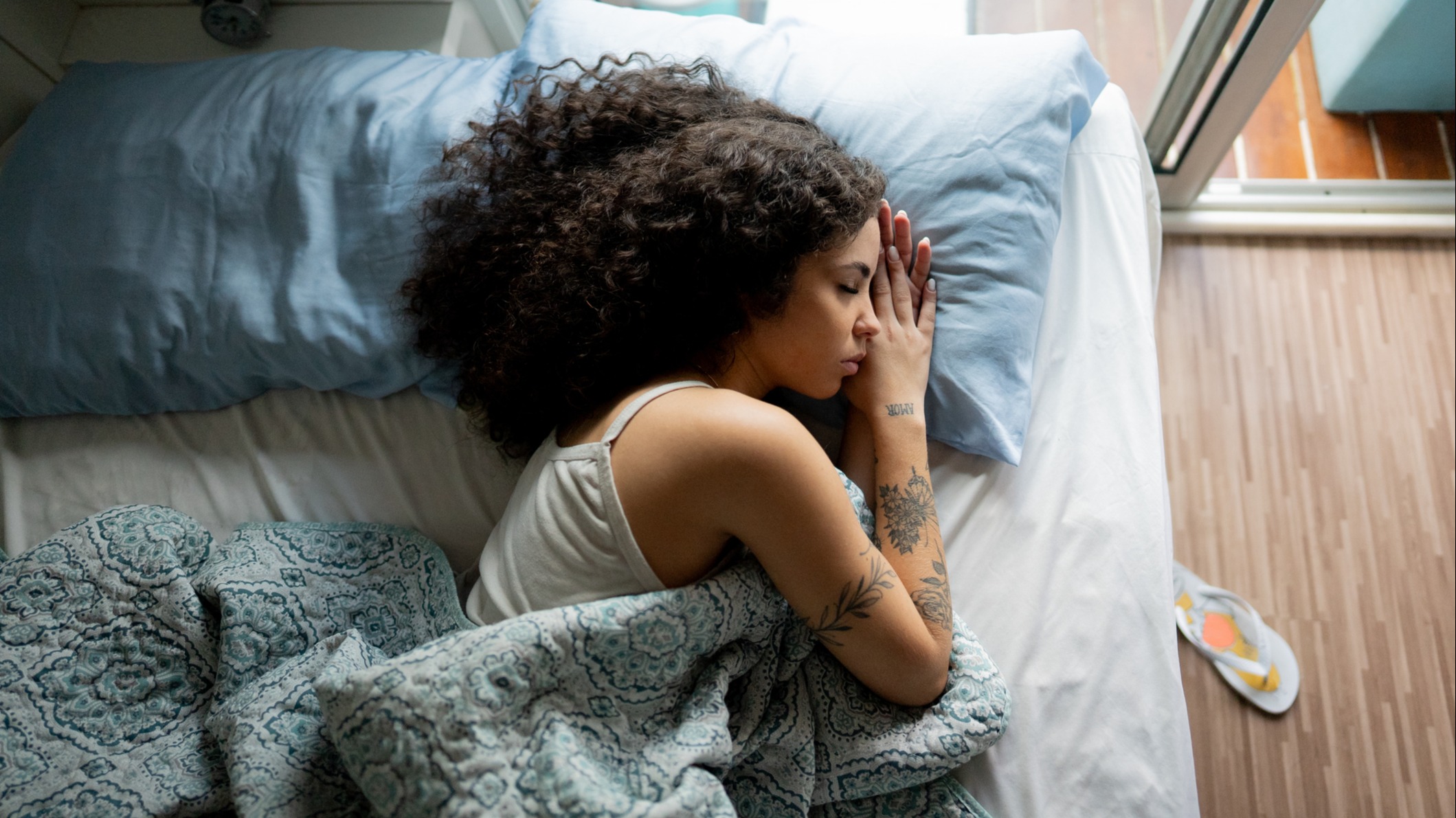 A young woman sleeps restfully in a gently lit bedroom.