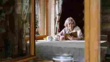 Senior woman sitting at a quiet table while reading.