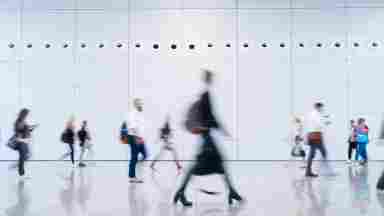 Blurred business people walking through a modern, minimalist building. 