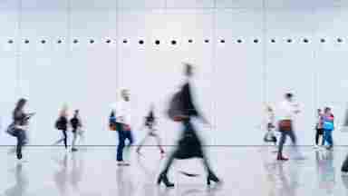 Blurred business people walking through a modern, minimalist building.
