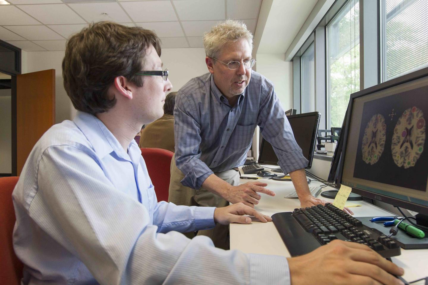 Bart Rypma, Ph.D. looking at images of a brain on a computer with a colleague.