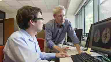 Bart Rypma, Ph.D. looking at images of a brain on a computer with a colleague.