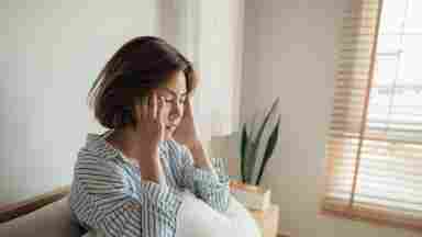 Young woman with high fever coughing and taking a medicine in the bed.