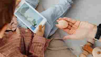 Child playing with their phone while a hand presents a brain-shaped eraser to them