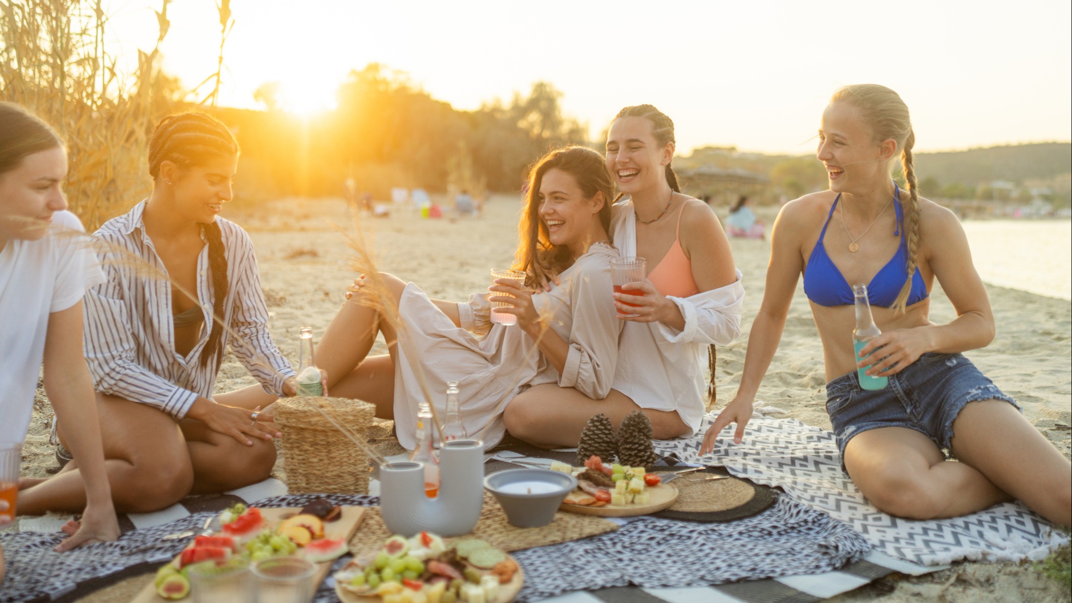 A group of young people enjoy a summer picnic on the beach.