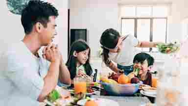 A happy, Asian family having breakfast together at home.