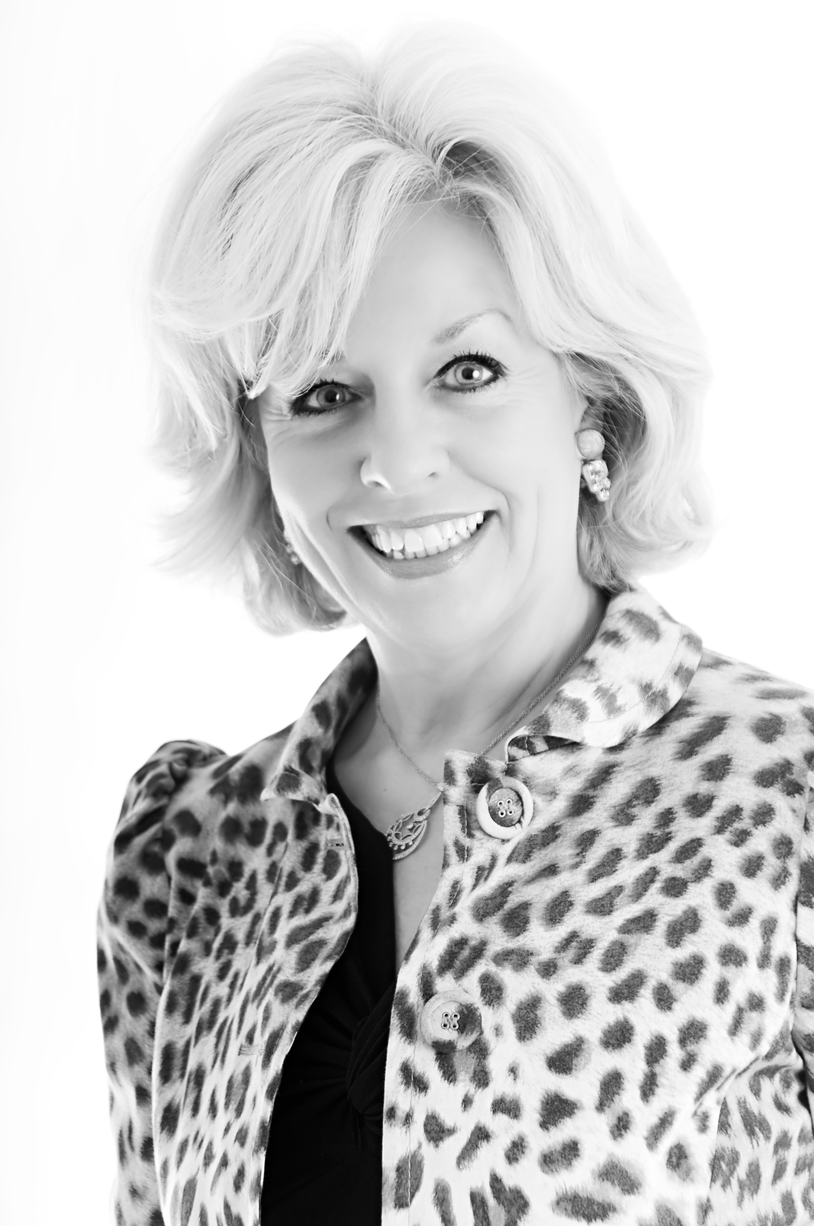 A black and white headshot of Dr. Sandra Chapman smiling and wearing a leopard print jacket with a dark blouse.