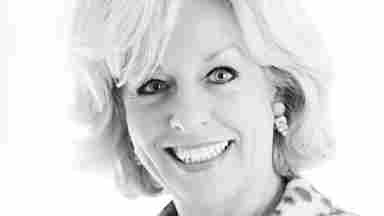A black and white headshot of Dr. Sandra Chapman smiling and wearing a leopard print jacket with a dark blouse.