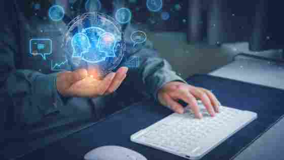 Person holding a glowing AI brain hologram while typing on a white keyboard, surrounded by blue digital icons.