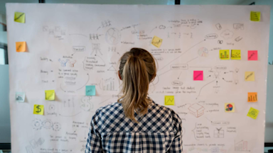 Woman sketching a colorful business plan on a placard at a creative office.