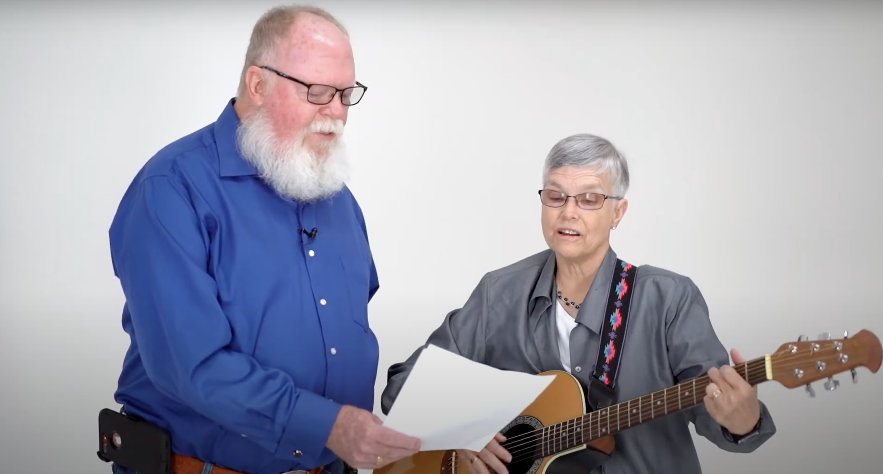 Steve and Sue sing while playing an acoustic guitar.