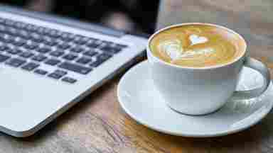 Cup of coffee on saucer next to laptop