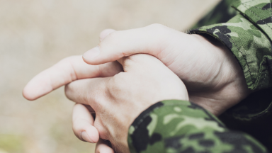 A military service member folds their hands.