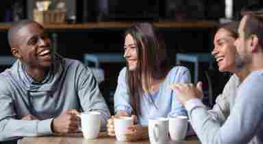 A happy group of people are conversing over coffee. 