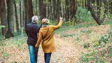 A couple walks in a park in autumn.
