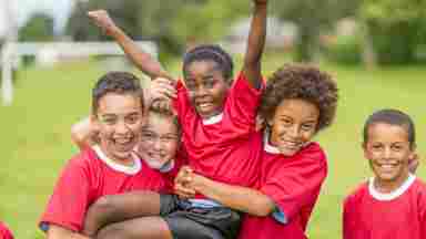 A happy diverse group of kids/children/youths in red uniforms on a field. IStock# 497272583
