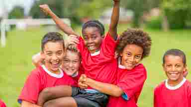 A happy diverse group of kids/children/youths in red uniforms on a field. IStock# 497272583