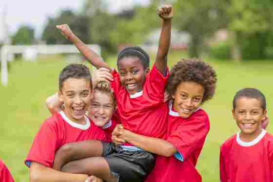 A happy diverse group of kids/children/youths in red uniforms on a field. IStock# 497272583