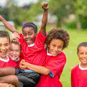 A happy diverse group of kids/children/youths in red uniforms on a field. IStock# 497272583