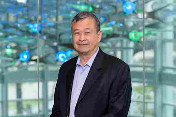 Dr. Geoffrey Ling in a black suit in front of a sculpture