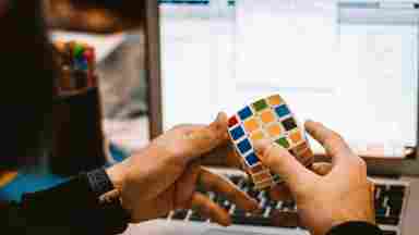 A pair of hands working to solve a Rubik's cube puzzle.