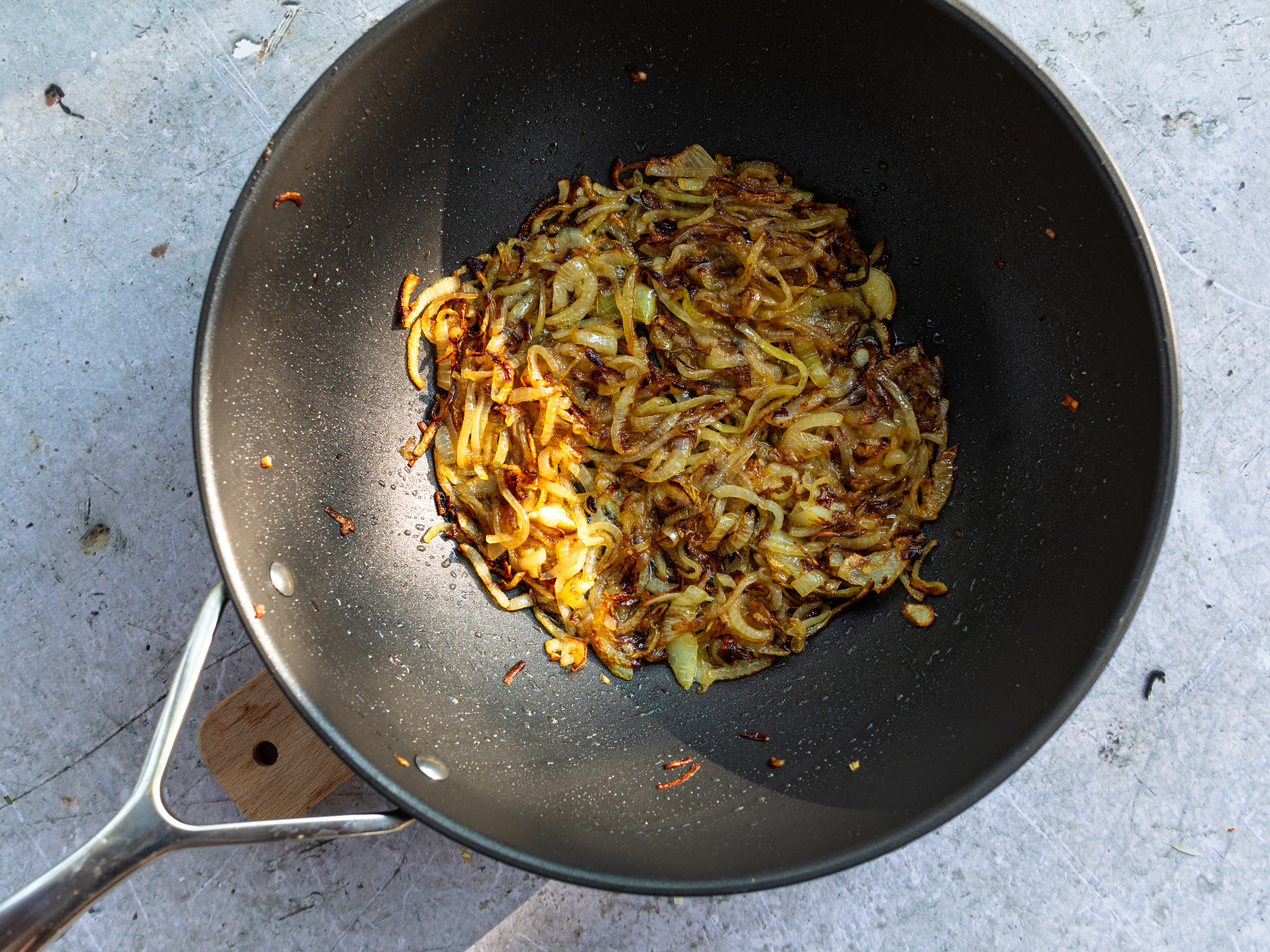 Schritt 3:  Das Olivenöl in einer grossen Pfanne erhitzen, die Zwiebeln und einen TL Zucker beigeben und langsam bei niedriger Hitze schmoren, bis sie gut gebräunt sind