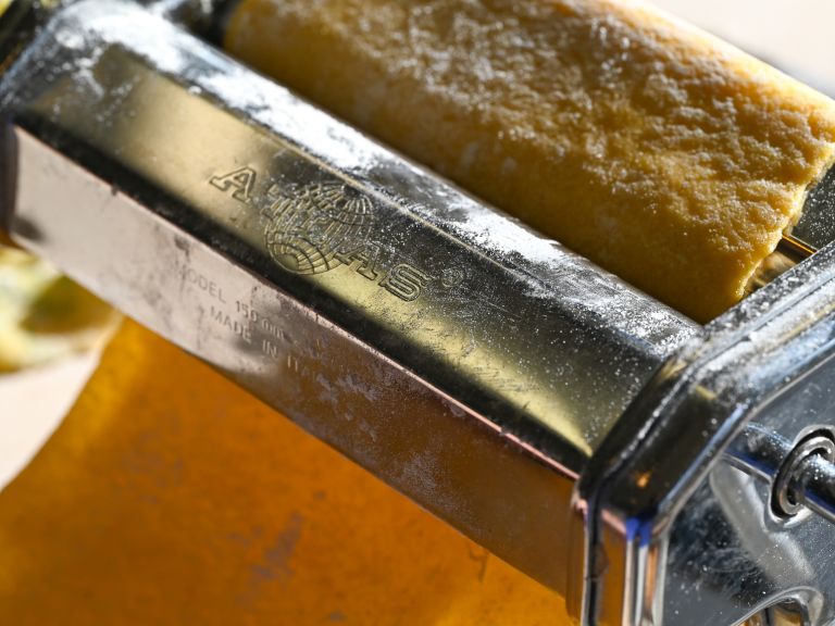 Schritt 3: Die einzelnen Teigstücke mit der Handfläche auf zirka einen halben Zentimeter flach drücken und in der Pastamaschine zu langen Teigblättern ausrollen