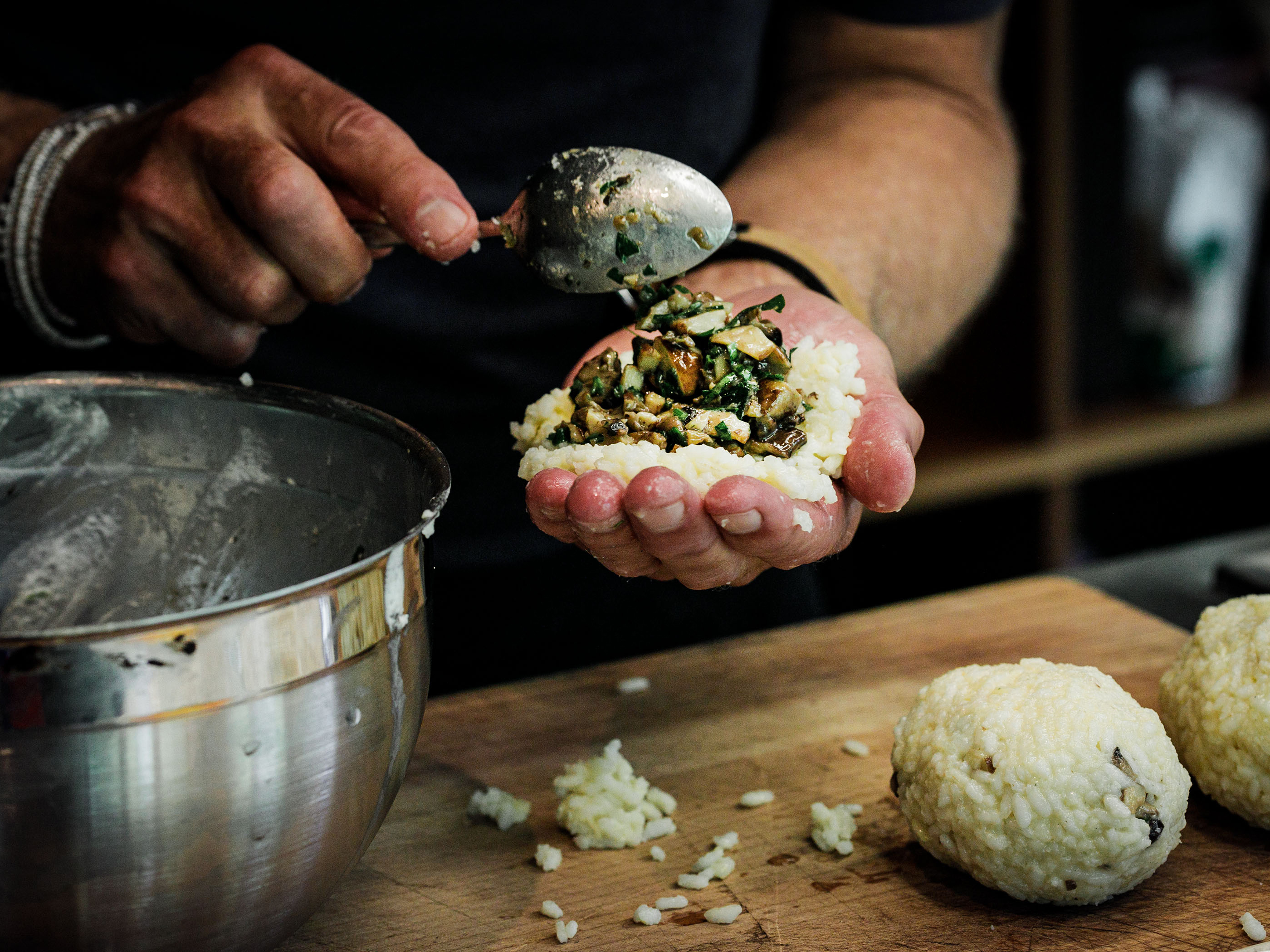 Schritt 3: Eine Handvoll der gekochten Reismischung auf der Handfläche ausbreiten und ein Sechstel der Pilzmischung in die Mitte geben