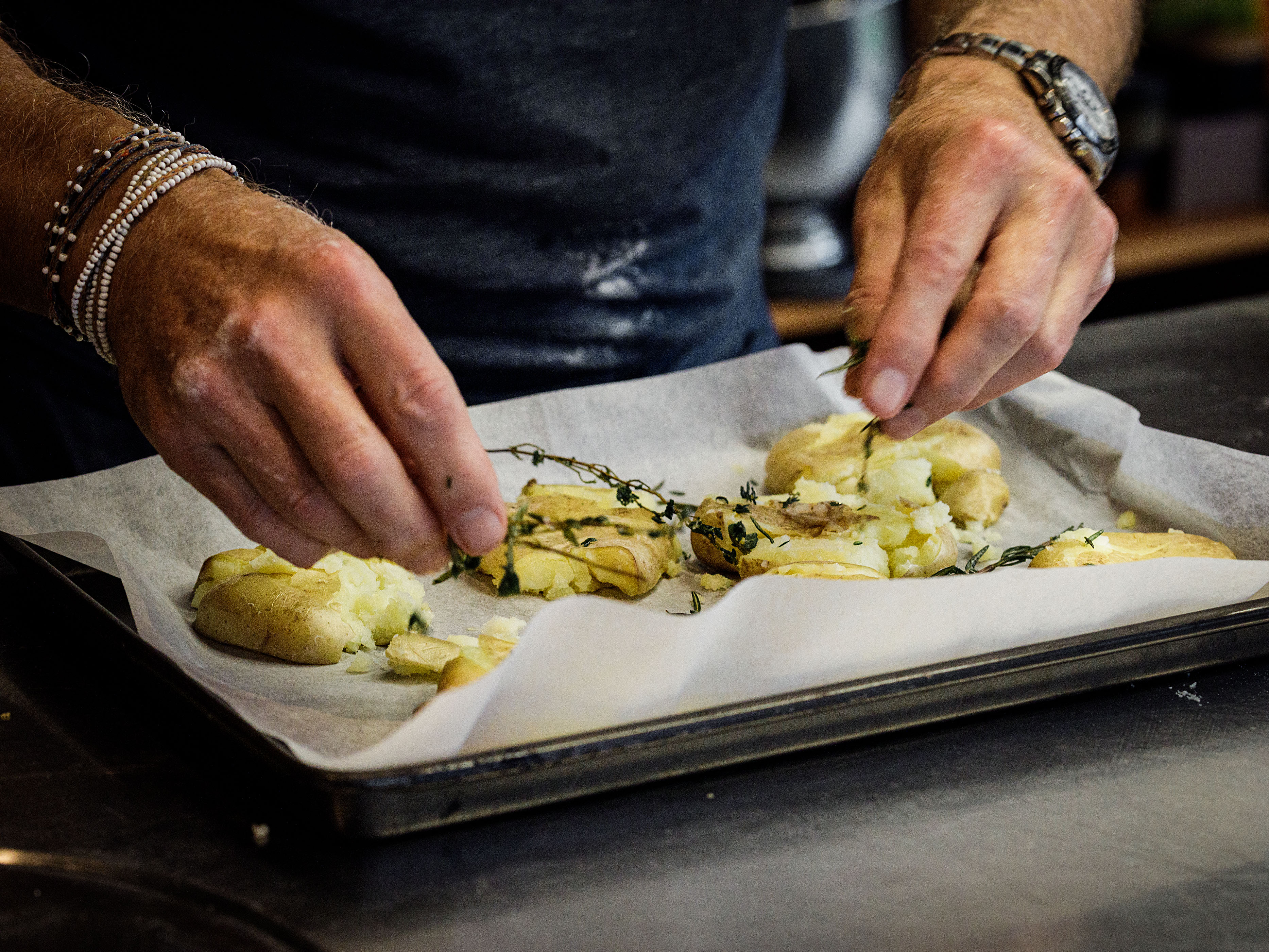 Schritt 2: Kartoffeln mit Olivenöl, Salz und Pfeffer sowie Thymianzweig und Knoblauchzehen grosszügig beträufeln
