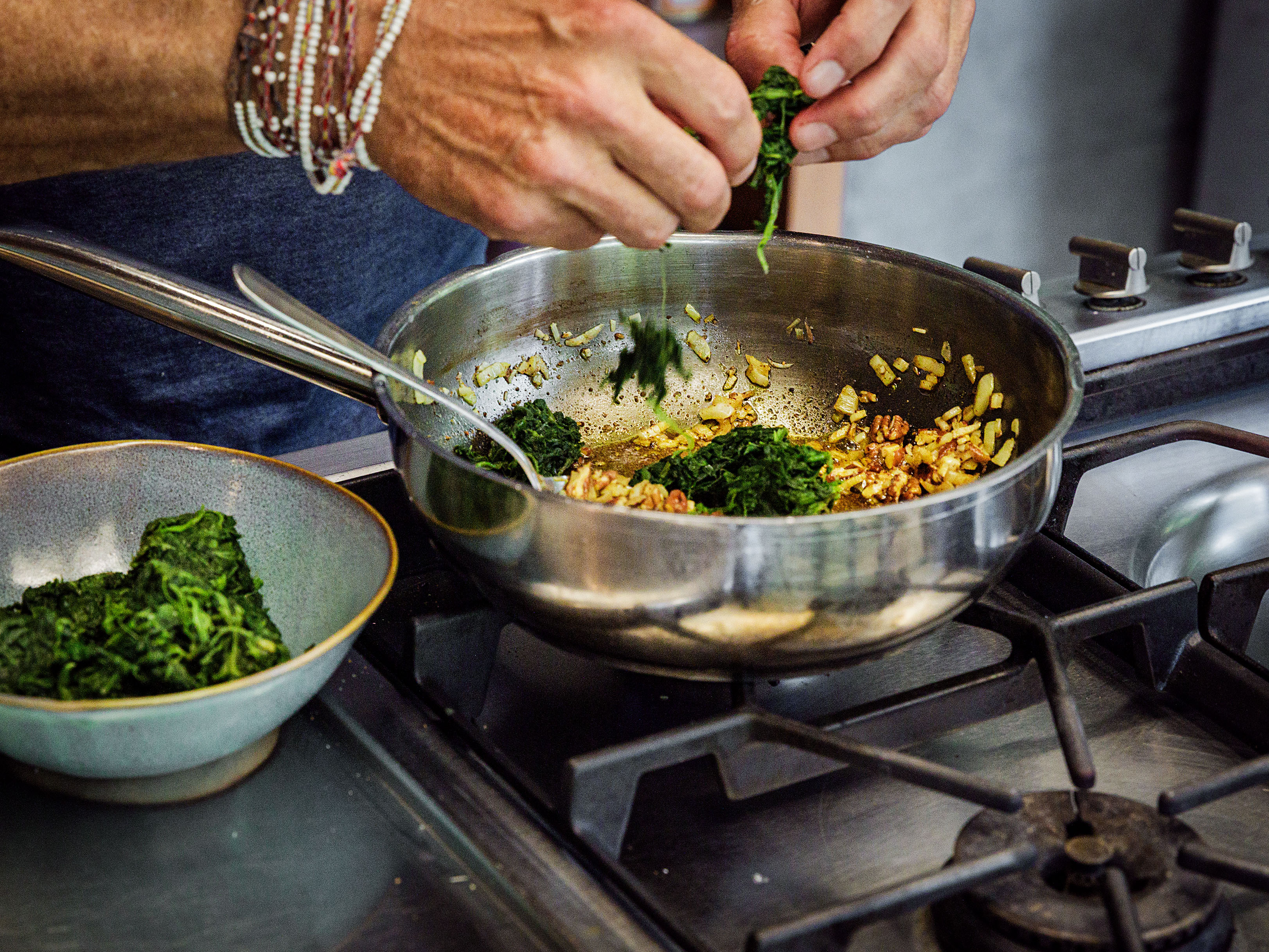 Schritt 2: Den gefrorenen Spinat zur Zwiebelmischung in die Pfanne geben