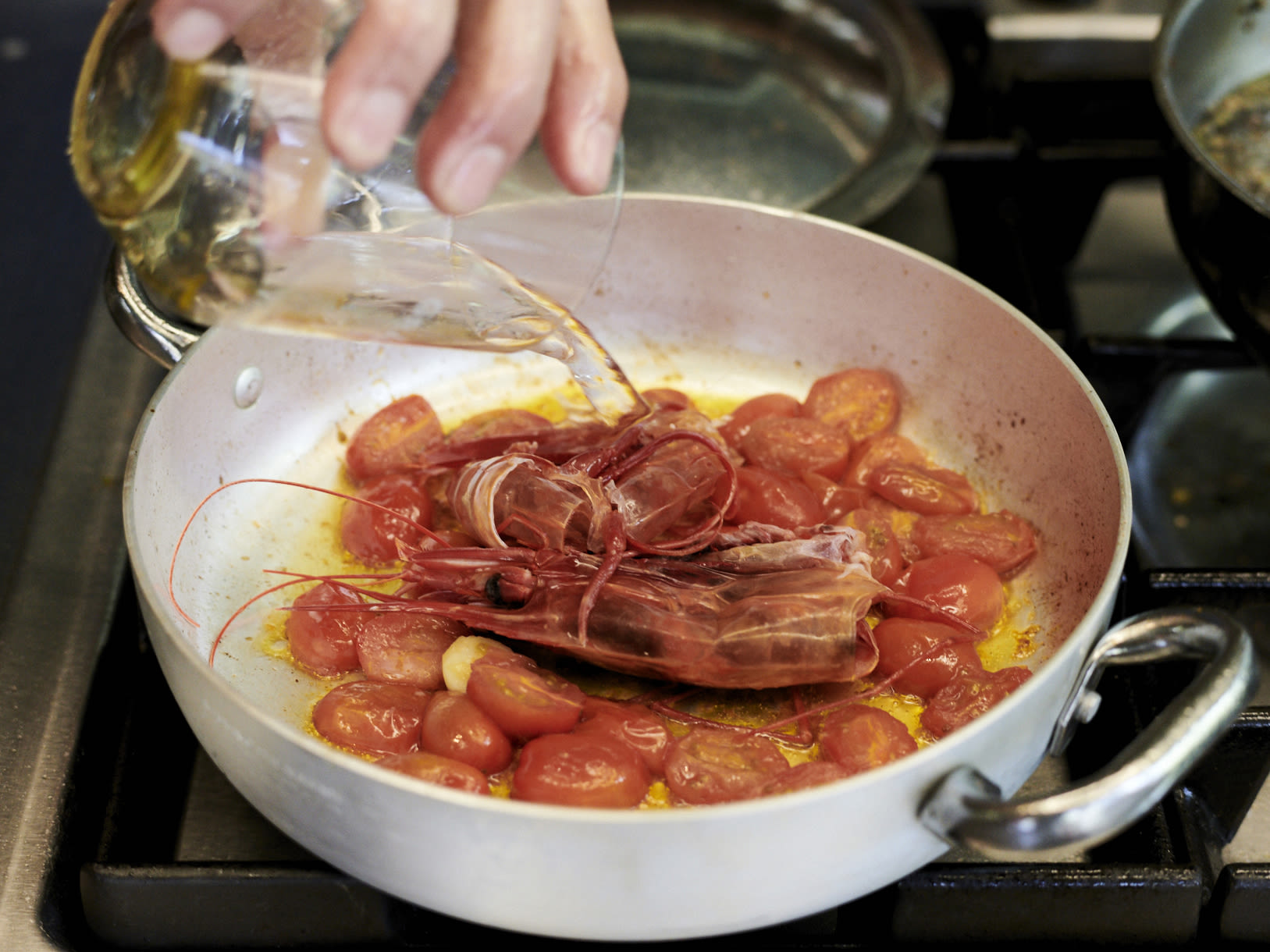 Schritt 1: Die Tomatenhälften in Olivenöl zusammen mit der Knoblauchzehe und den Schalen und Köpfen der Gamberi sanft zugedeckt 