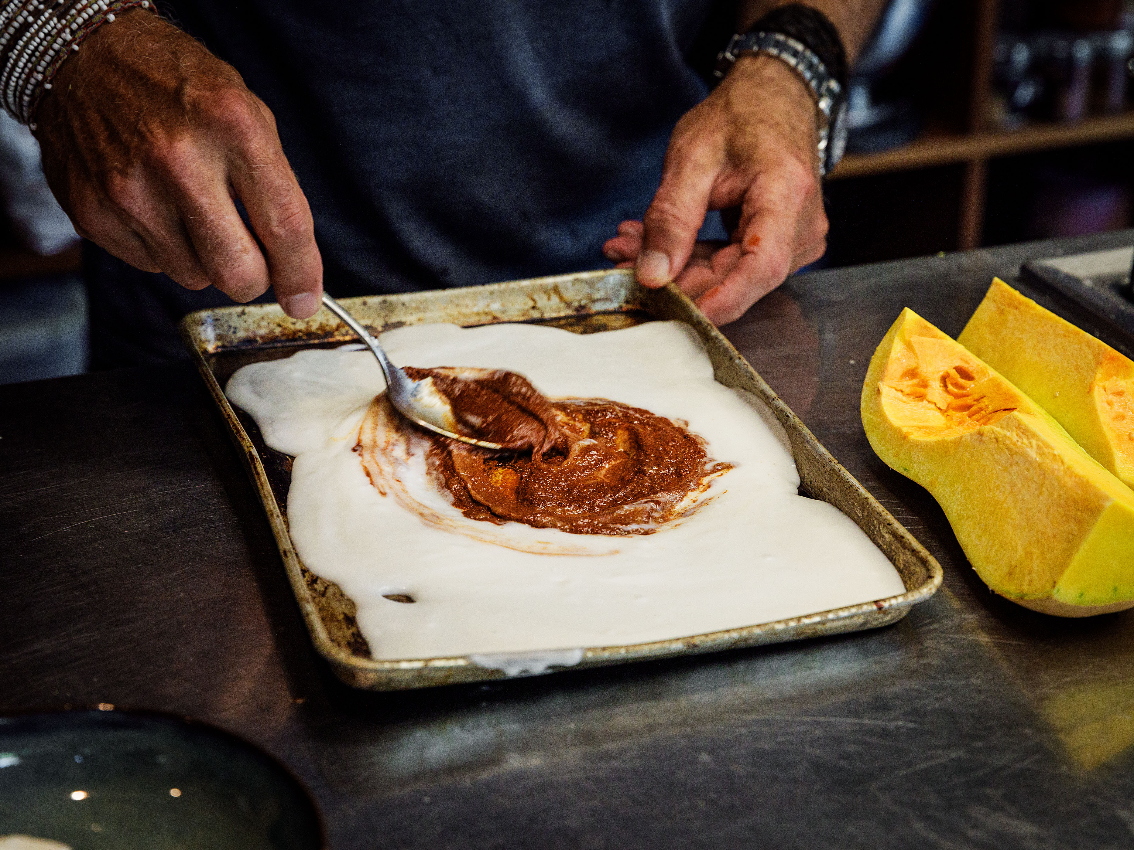 Schritt 1: Currypaste, Kokosmilch, Butternusskürbis, Tomaten und Kichererbsen auf einem Backblech vermengen