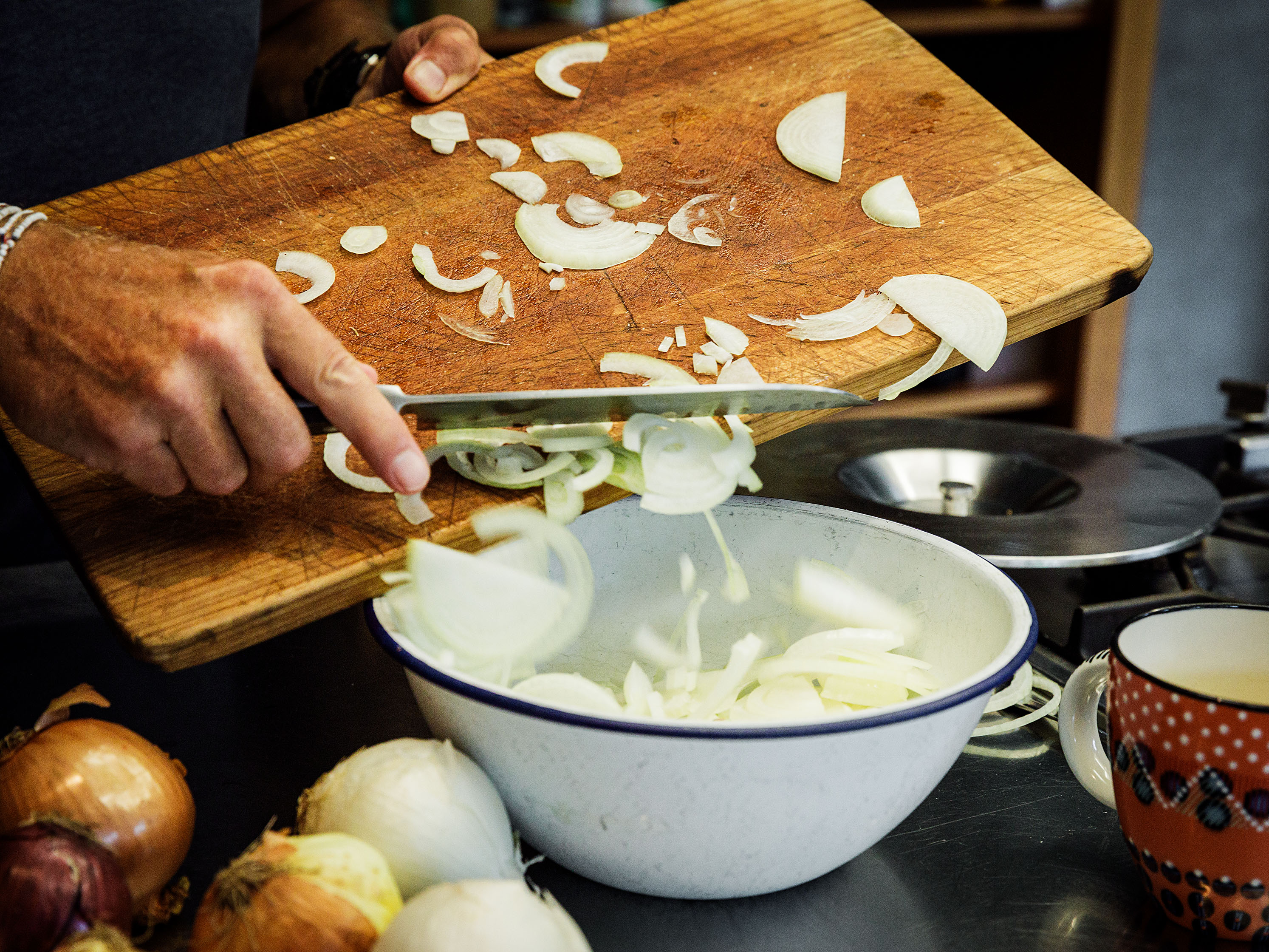Schritt 3: Die Zwiebeln längs halbieren, dann schälen und längs in feine Streifen schneiden