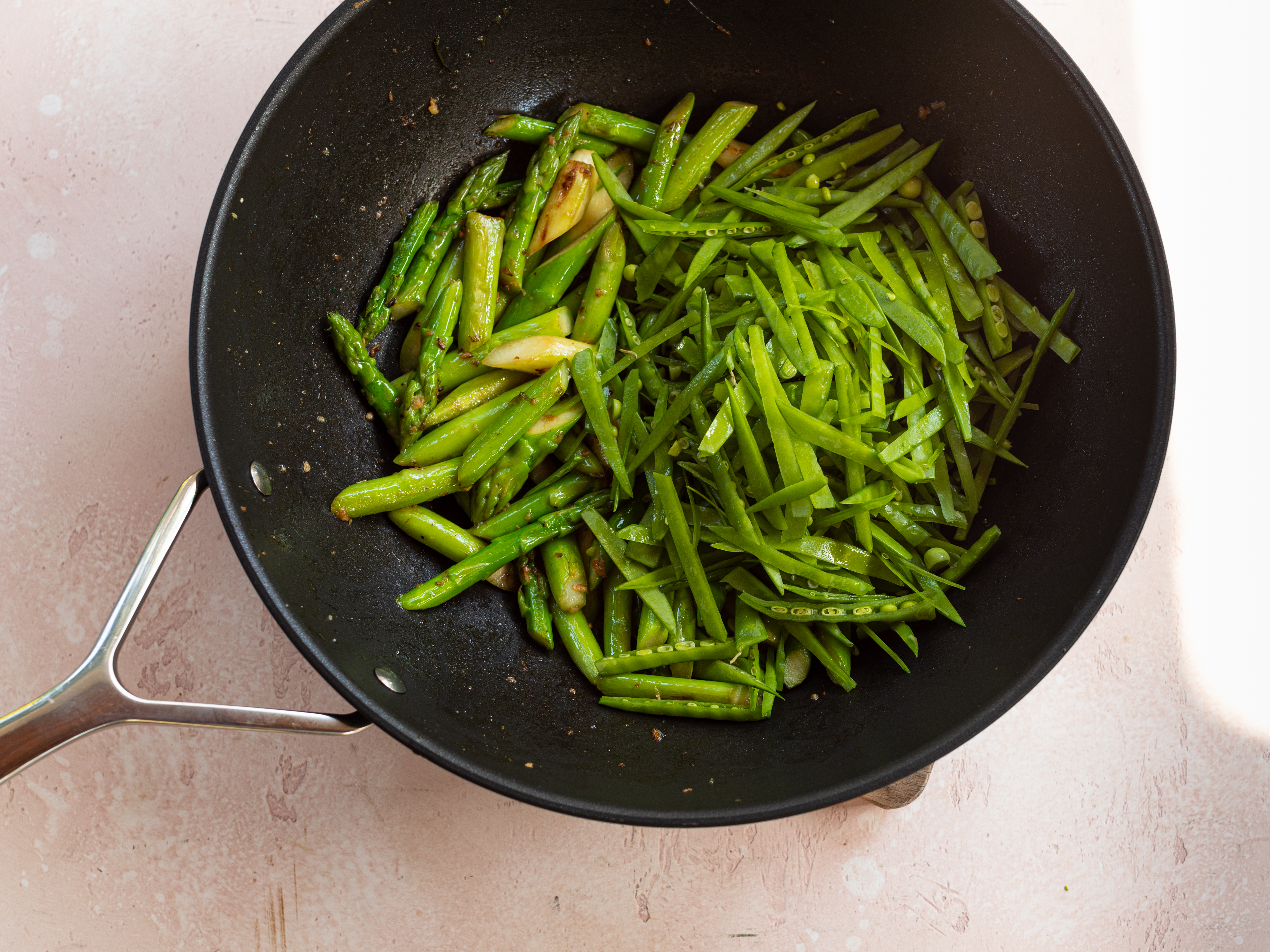 Schritt 3: Den grünen Spargel und dann die Zuckerschoten in den Wok geben und für etwa 5-7 Minuten braten