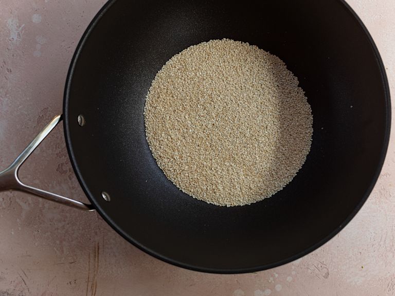 Schritt 2: In einer Pfanne ohne Öl die Sesamsamen bei mittlerer Hitze rösten, bis sie goldbraun sind Schritt 2: In einer Pfanne ohne Öl die Sesamsamen bei mittlerer Hitze rösten, bis sie goldbraun sind