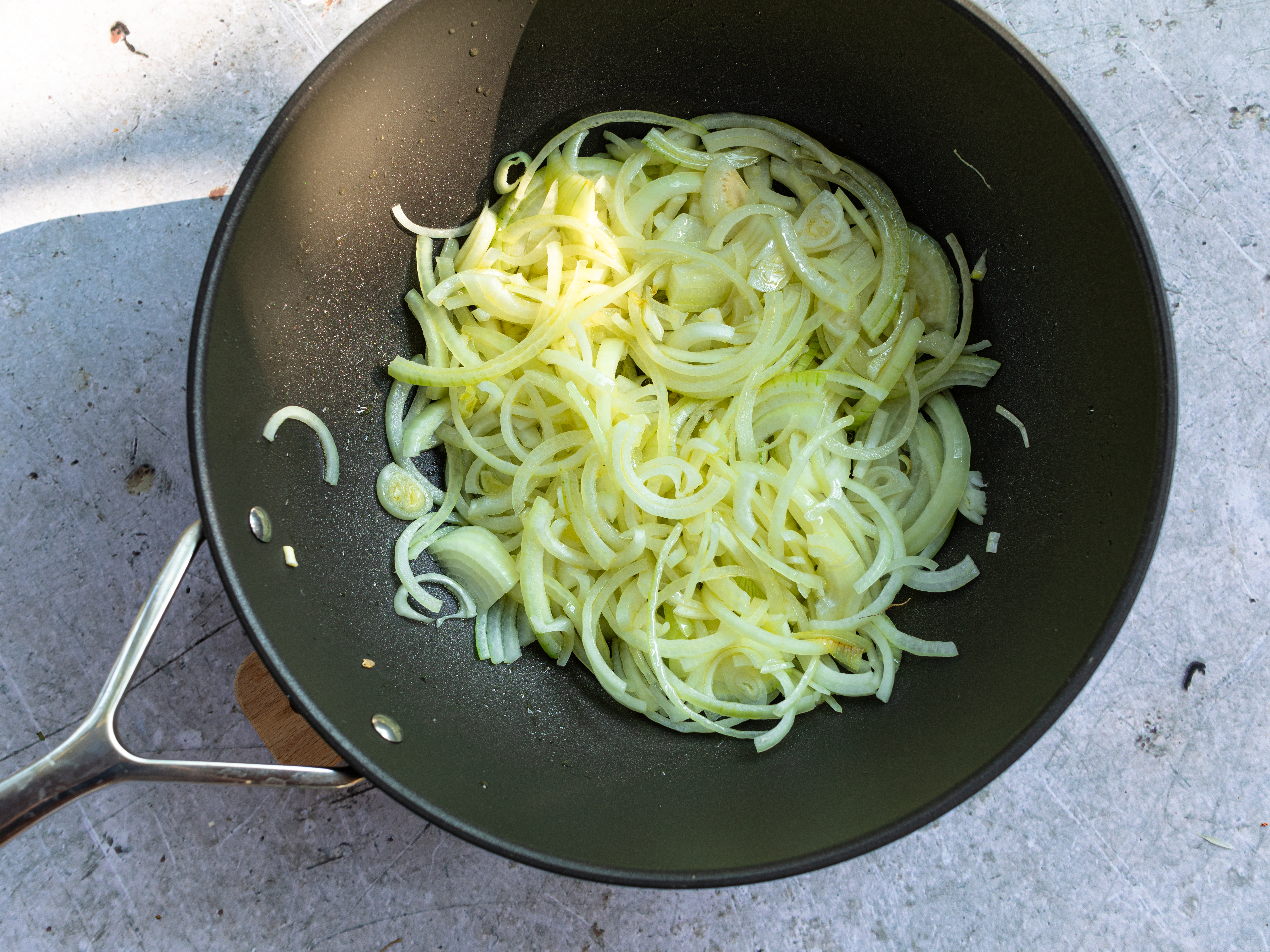 Schritt 3:  Das Olivenöl in einer grossen Pfanne erhitzen, die Zwiebeln und einen TL Zucker beigeben und langsam bei niedriger Hitze schmoren, bis sie gut gebräunt sind