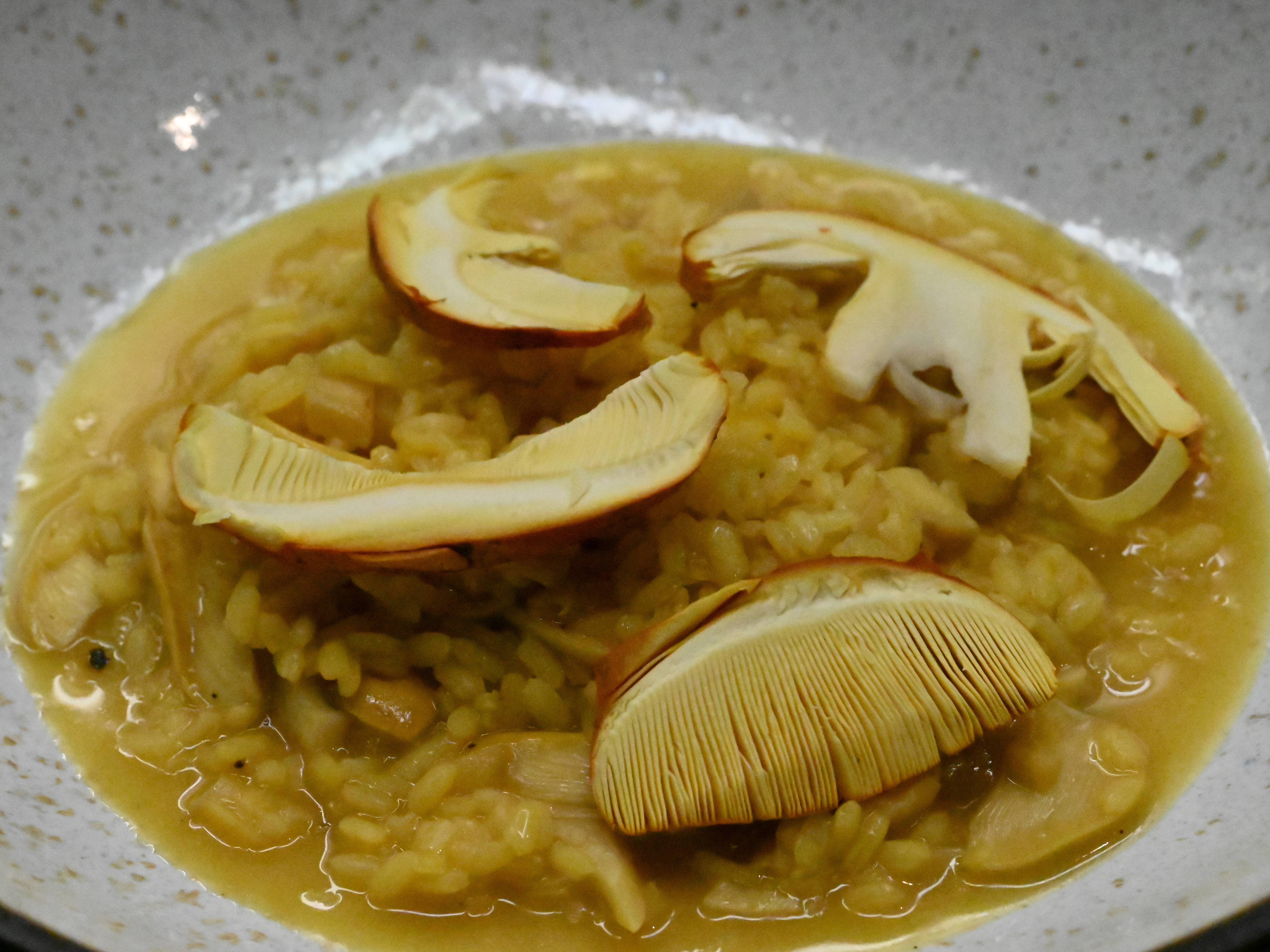 Schritt 3: Risotto mit den zurückbehaltenen Pilzscheiben dekorieren, mit der Petersilie bestreuen und mit zusätzlichem Parmesan servieren
