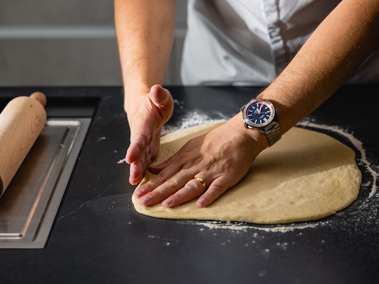 Schritt 1: Den Teig für den Chili-Käse-Zopf auf einer bemehlten Arbeitsfläche zu einem Rechteck ausrollen und die Füllung darauf verteilen. Schritt 1: Den Teig für den Chili-Käse-Zopf auf einer bemehlten Arbeitsfläche zu einem Rechteck ausrollen und die Füllung darauf verteilen.