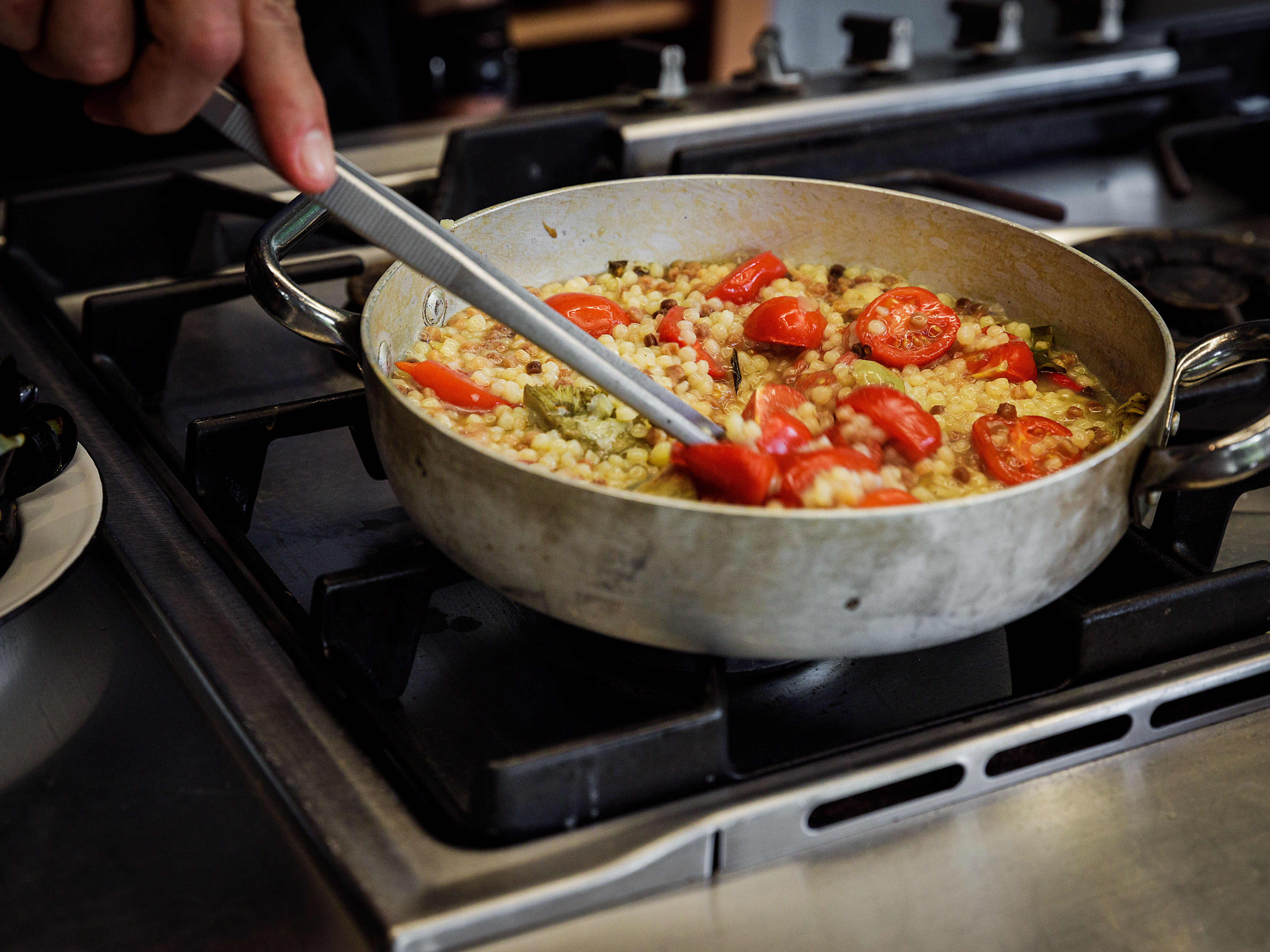 Schritt 3: Tomaten, Fischfond und Fregola in die Pfanne geben, umrühren und aufkochen